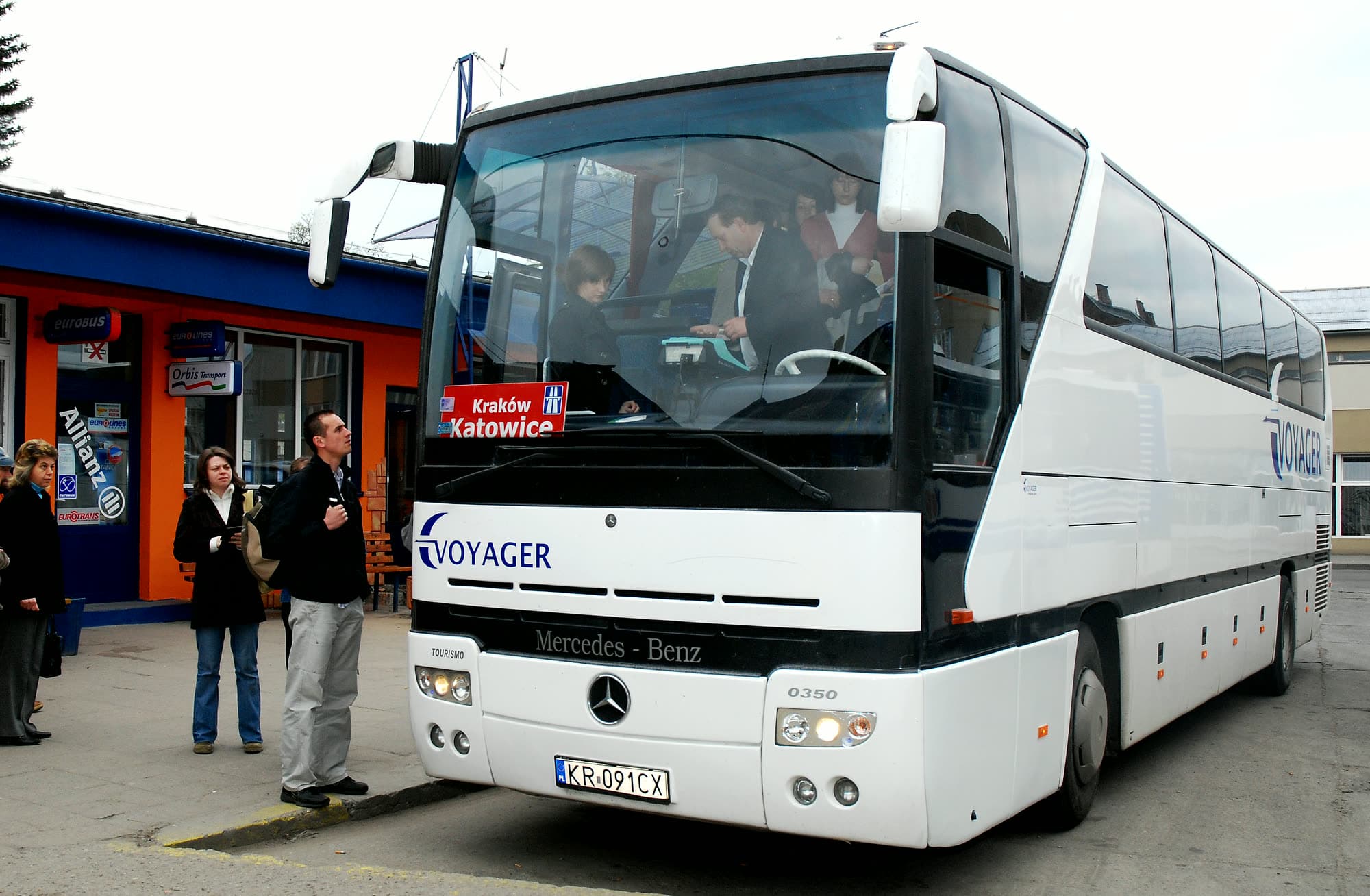 Pasażerowie czekający na autokar Voyagera przy stanowisku dworcowym